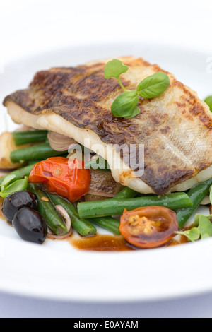 Pan fried fish on a bed of vegetables.