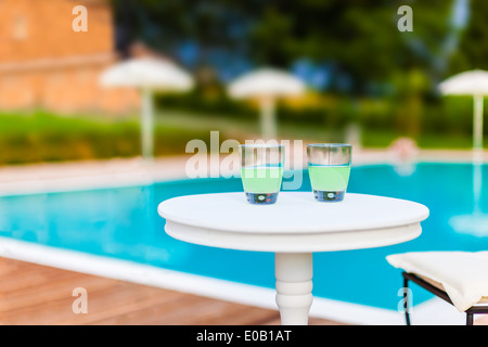two drinks on a white table with a swimming pool as background Stock Photo