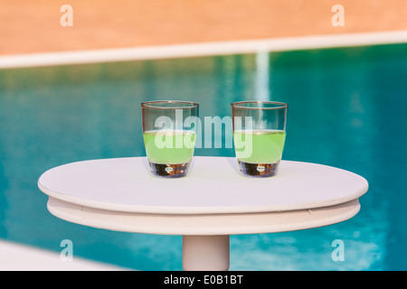two drinks on a white table with a swimming pool as background Stock Photo
