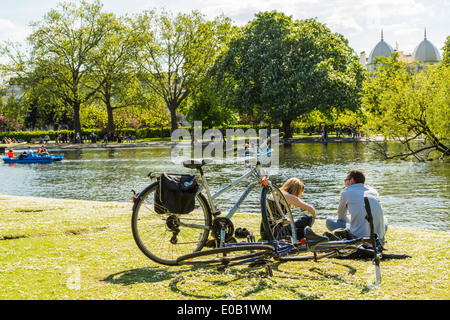 Young people relaxing beside the boating lake on a sunny day in Regents Park London UK Stock Photo
