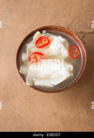 Wonton soup with chili in wooden bowl Stock Photo