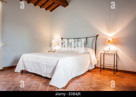 a luxurious bedroom with a lamp over a bed side table Stock Photo