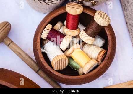 various multi colored spools in a wooden bowl Stock Photo