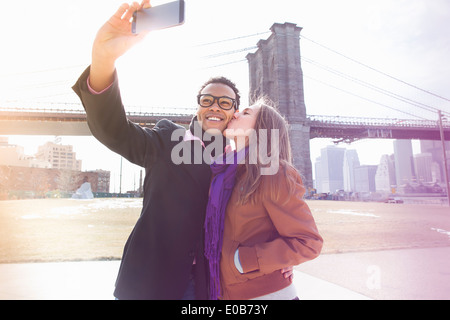 Young couple taking self portrait next to Brooklyn Bridge, New York, USA