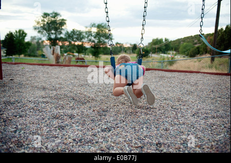 Rear view of female toddler lying on park swing Stock Photo