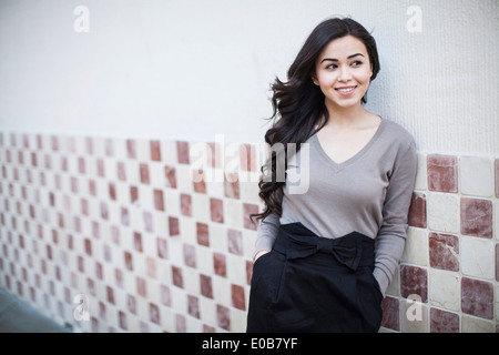 Portrait of young woman, leaning against tiled wall Stock Photo