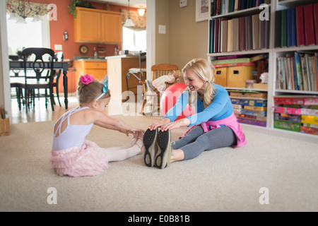 Mother and young daughter warming up for ballet in sitting room Stock Photo