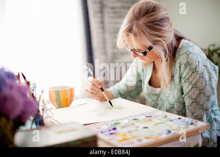 Mature female artist watercolour painting in studio Stock Photo