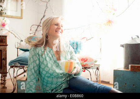 Mature woman sitting on floor in living room Stock Photo