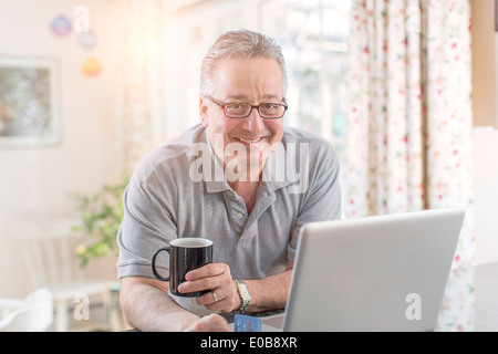 Mature man at home using laptop Stock Photo
