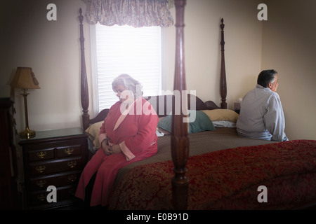 Mature couple sitting on opposite sides of bed Stock Photo