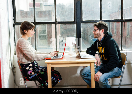 Male and female designers working on laptops in studio Stock Photo