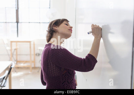 Young female designer drawing on whiteboard Stock Photo