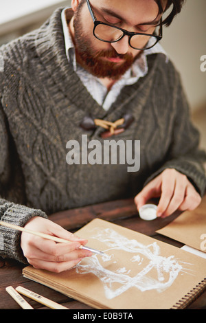 Image of serious young man in sweater drawing Stock Photo
