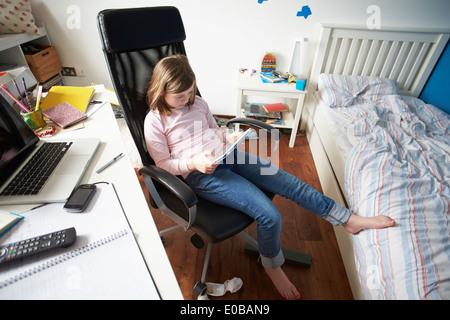 Girl Using Digital Tablet In Bedroom Stock Photo