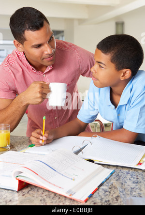 Father Helping Son With Homework In Kitchen Stock Photo