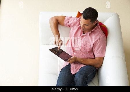 Overhead View Of Man Relaxing On Sofa Using Digital Tablet Stock Photo