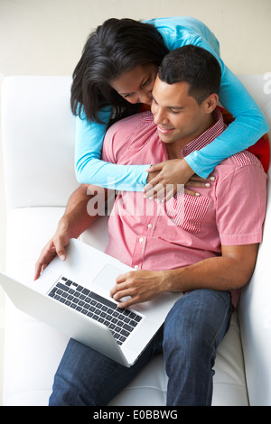 Overhead View Of Couple Relaxing On Sofa Using Laptop Stock Photo