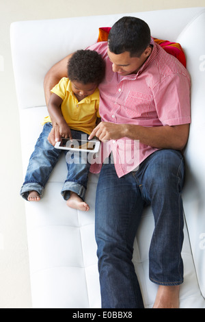 Overhead View Of Father And Son On Sofa Using Digital Tablet Stock Photo