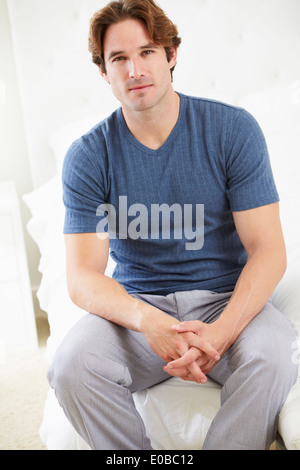 Man Sitting On Bed Wearing Pajamas Stock Photo