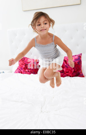 Girl Jumping On Bed Wearing Pajamas Stock Photo