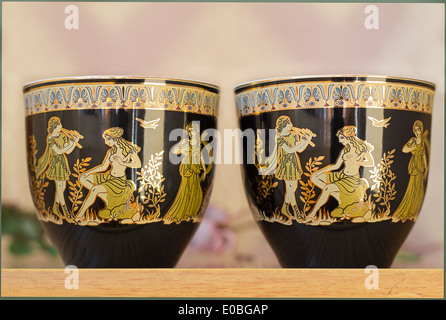 The beautiful tea cups decorated with a list with gold with the image of scenes from antique life. Stock Photo