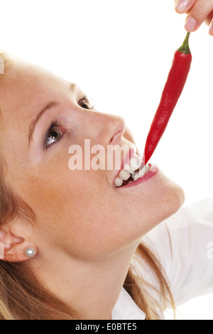 A young woman bites in a Chilli pod. Before white background, Eine junge Frau beisst in eine Chilli Schote. Vor weissem Hintergr Stock Photo