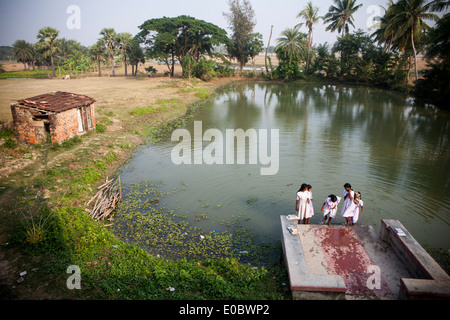 Indian school girls wash their feet beside a pond Stock Photo