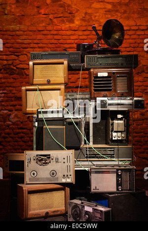 Tower - Stacks of Vintage Radios, stereo cassette deck, players and gramophone with red brick wall background Stock Photo