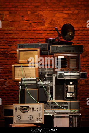 Tower - Stacks of Vintage Radios, stereo cassette deck, players and gramophone with red brick wall background Stock Photo