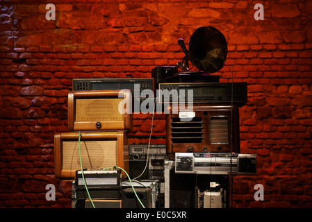 Tower - Stacks of Vintage Radios, stereo cassette deck, players and gramophone with red brick wall background Stock Photo