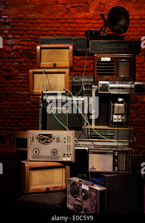 Tower - Stacks of Vintage Radios, stereo cassette deck, players and gramophone with red brick wall background Stock Photo