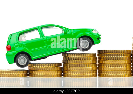 A model Car stands on coins. Rising autocosts with cost of petrol, assurance and taxes., Ein Modell Auto steht auf Muenzen. Stei Stock Photo