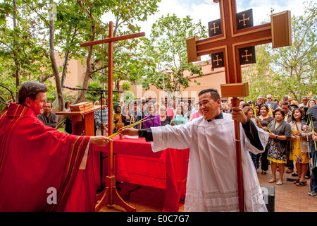 A Vietnamese seminarian intern holding a cross receives a palm frond from the pastor of St. Timothy's Catholic Church, Laguna Niguel, CA, as the congregation gathers for Palm Sunday mass. Note palm fronds held by group. Stock Photo