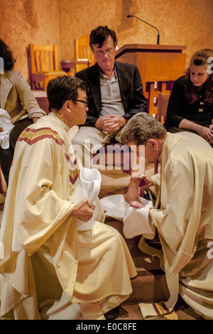 The robed pastor of St. Timothy's Catholic Church, Laguna Niguel, CA, washes the feet of parishioners on Holy Thursday mass in memory of Christ washing the feet of his disciples at the Last Supper. Note age range. Stock Photo