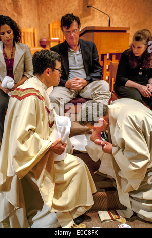 The robed pastor of St. Timothy's Catholic Church, Laguna Niguel, CA, washes the feet of parishioners on Holy Thursday mass in memory of Christ washing the feet of his disciples at the Last Supper. Note age range. Stock Photo