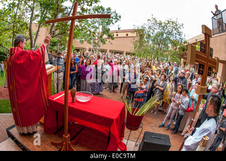 The robed pastor of St. Timothy's Catholic Church in Laguna Niguel, CA addresses parishioners on Palm Sunday in the church courtyard. Note palm fronds. Stock Photo