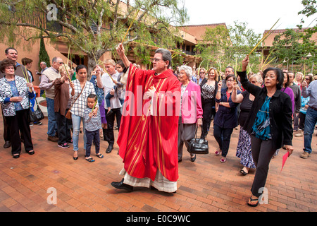 The robed pastor of St. Timothy's Catholic Church in Laguna Niguel, CA leads his  parishioners on a march on Palm Sunday in the church courtyard. Note palm fronds being carried. Stock Photo