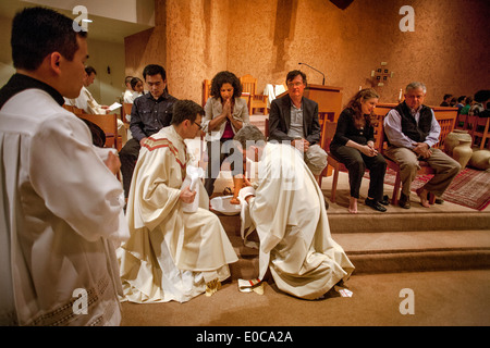 The robed pastor of St. Timothy's Catholic Church, Laguna Niguel, CA, washes the feet of parishioners on Holy Thursday mass in memory of Christ washing the feet of his disciples at the Last Supper. Note age range. Stock Photo