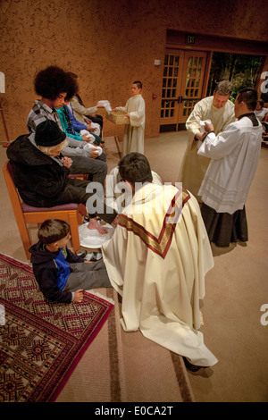 The robed pastor of St. Timothy's Catholic Church, Laguna Niguel, CA, washes the feet of parishioners on Holy Thursday mass in memory of Christ washing the feet of his disciples at the Last Supper. Note child. Stock Photo