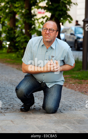 A man has a cardiac infarction or stroke on the street, Ein Mann hat einen Herzinfarkt oder Schlaganfall auf der Strasse Stock Photo