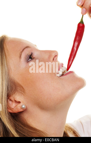 A young woman bites in a Chilli pod. Before white background, Eine junge Frau beisst in eine Chilli Schote. Vor weissem Hintergr Stock Photo