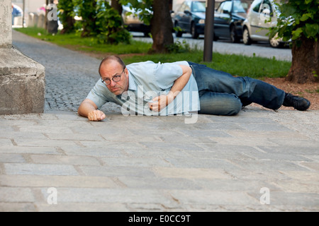 A man has a cardiac infarction or stroke on the street, Ein Mann hat einen Herzinfarkt oder Schlaganfall auf der Strasse Stock Photo