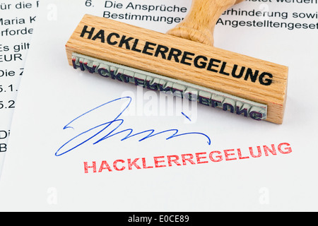 A stamp of wood lies on a document. Label Hacklerregelung, Ein Stempel aus Holz liegt auf einem Dokument. Aufschrift Hacklerrege Stock Photo