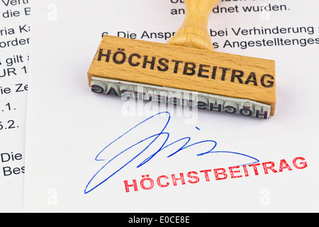 A stamp of wood lies on a document. Label Hoechstbeitrag, Ein Stempel aus Holz liegt auf einem Dokument. Aufschrift Hoechstbeitr Stock Photo