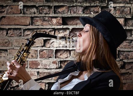 young beautiful woman in black hat with saxophone Stock Photo