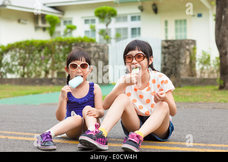 little Girls Eating Ice Cream and sitting before their house Stock Photo