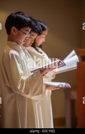 Young robed altar servers read the Daily Missal as they participate in Holy Thursday mass at St. Timothy's Catholic Church, Laguna Niguel, CA. Stock Photo