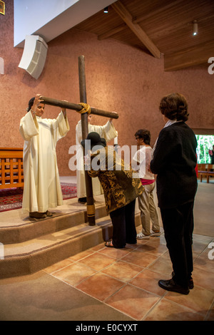 During the Good Friday mass at St. Timothy's Catholic Church, Laguna Niguel, CA, parishioners participate in the Solemn Veneration of the Cross. Note robed altar servers. Stock Photo