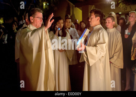 The robed pastor of St. Timothy's Catholic Church, Laguna Niguel, CA, reads from the gospel beside the Easter fire at the start of the Great Easter Vigil. Stock Photo